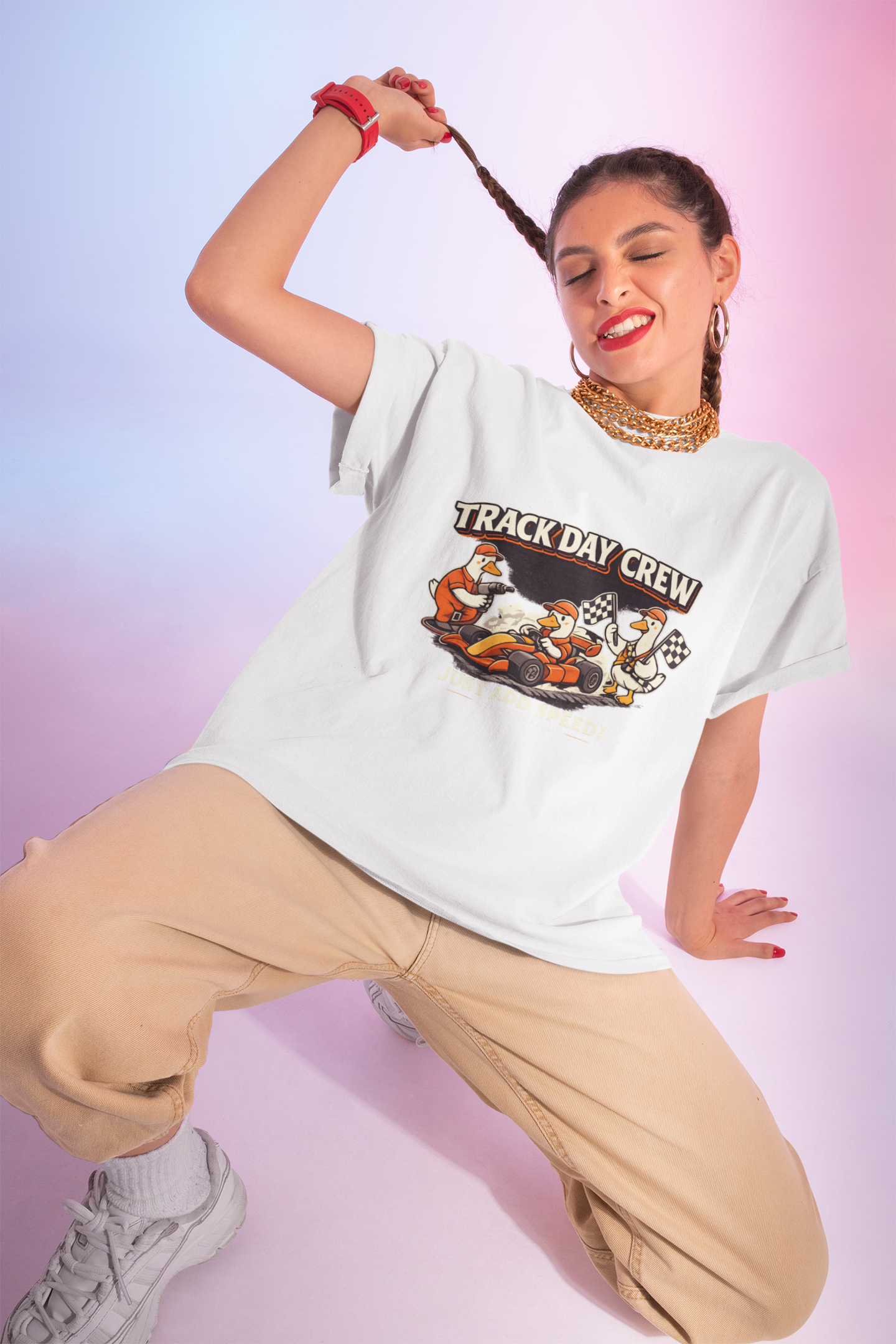 Woman wearing a 'Track Day Crew' white t-shirt with a graphic design on a gradient background
