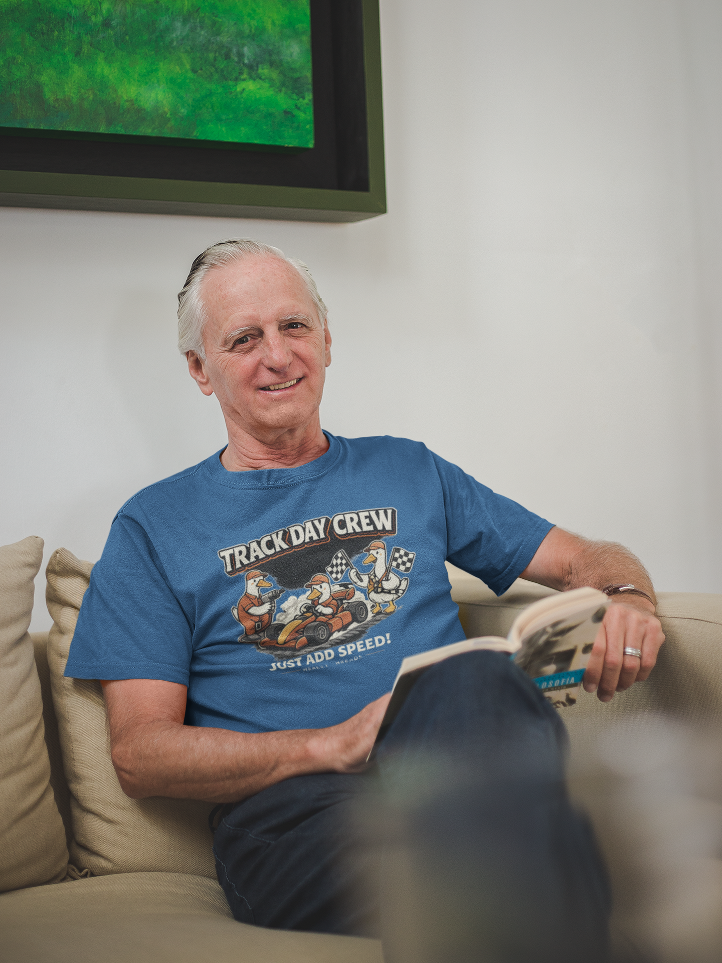 Man wearing a blue t-shirt with 'Track Day Crew' graphic on a gray background while sitting in chair