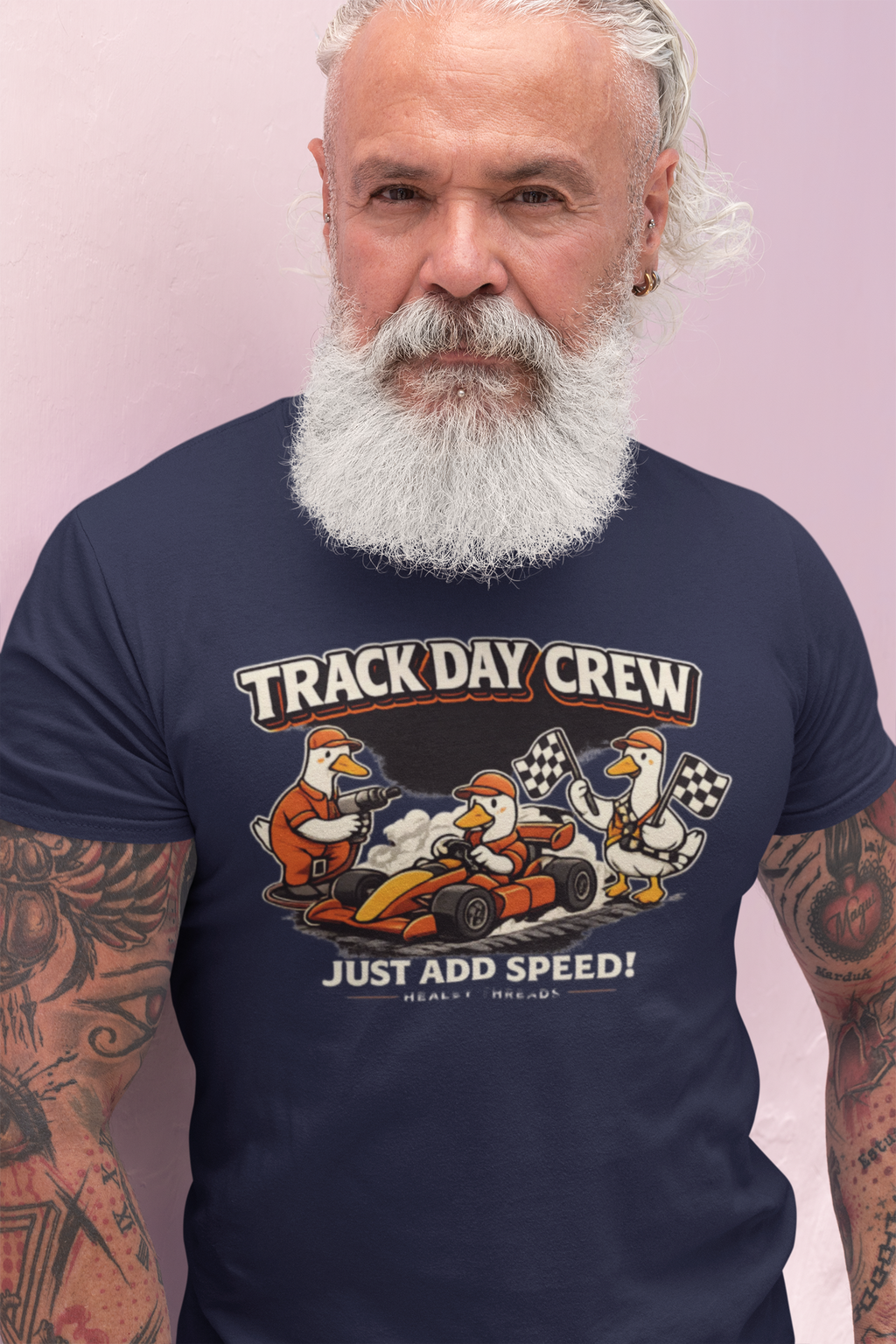Man wearing a navy blue t-shirt with 'Track Day Crew' graphic design on a light pink background