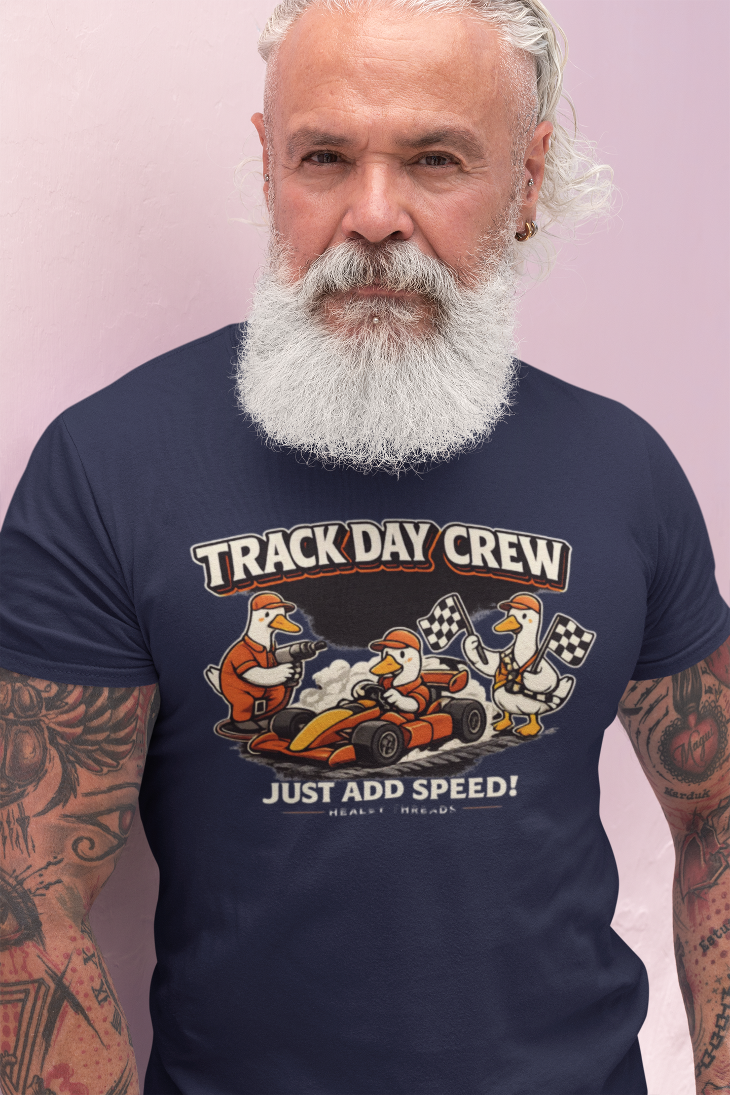 Man wearing a navy blue t-shirt with 'Track Day Crew' graphic design on a light pink background