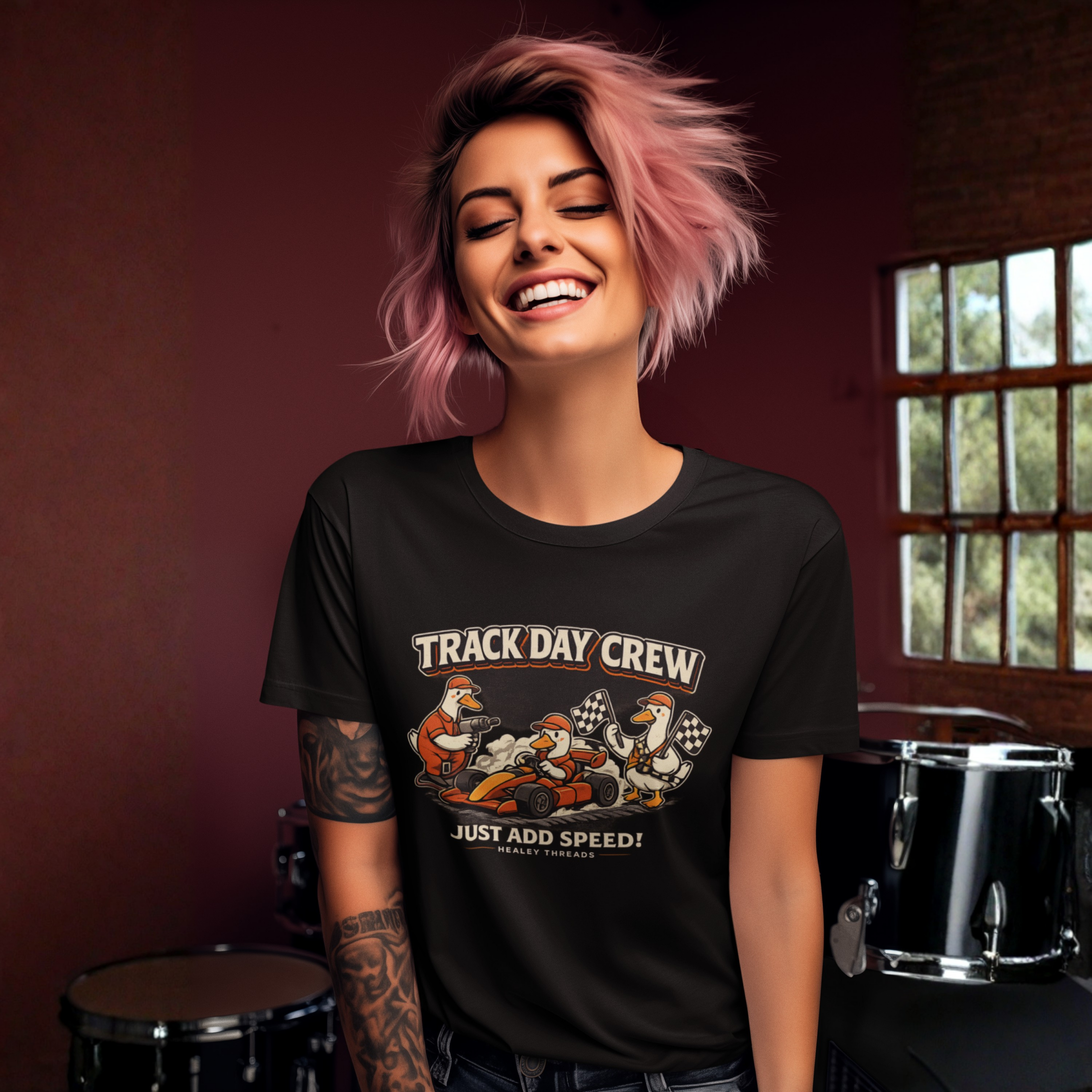 Woman wearing a black 'Track Day Crew' t-shirt with cartoon characters in a room with musical instruments.