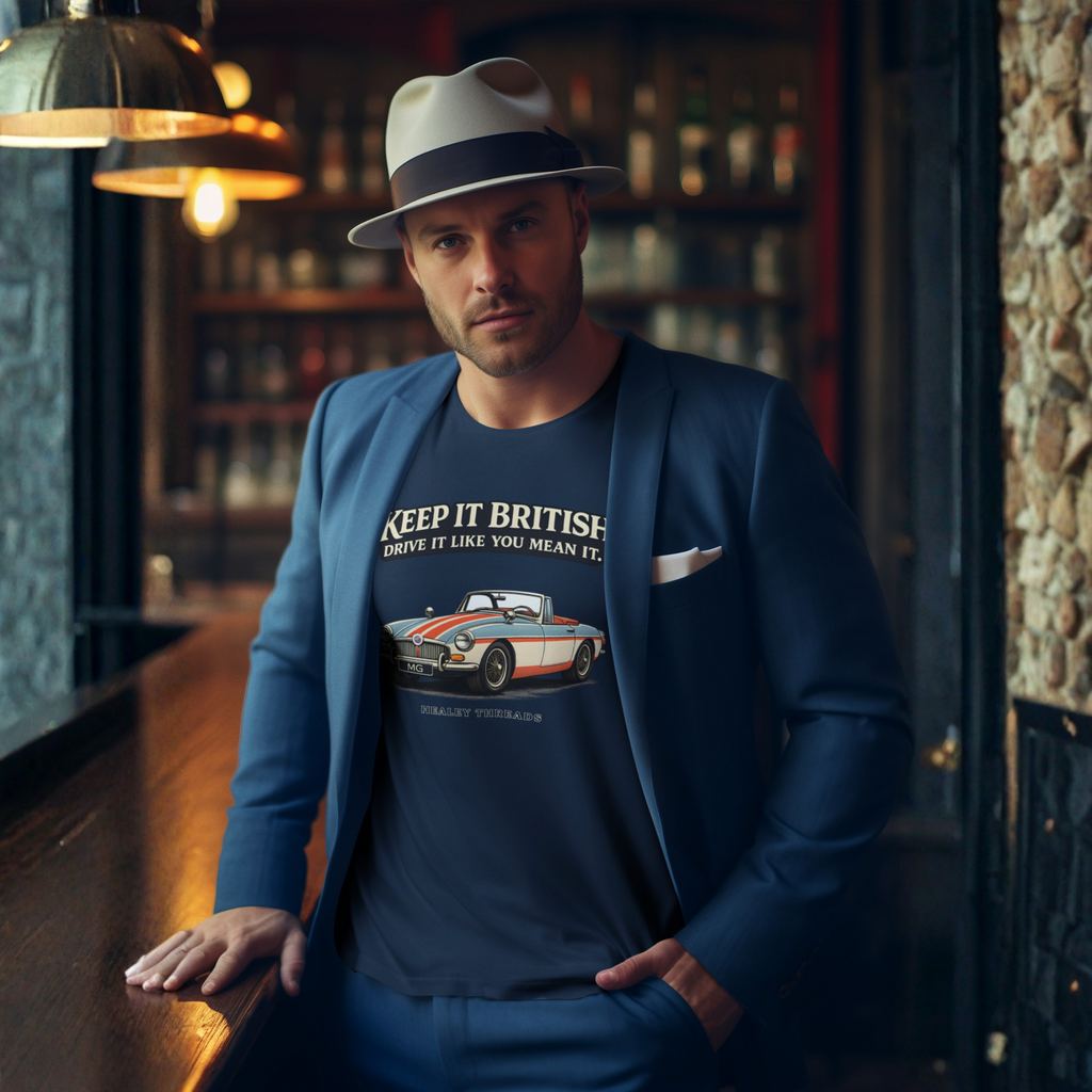 Man wearing a blue blazer and a navy blue t-shirt with a MGB car graphic and text, standing in a bar setting.