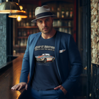 Man wearing a blue blazer and a navy blue t-shirt with a MGB car graphic and text, standing in a bar setting.