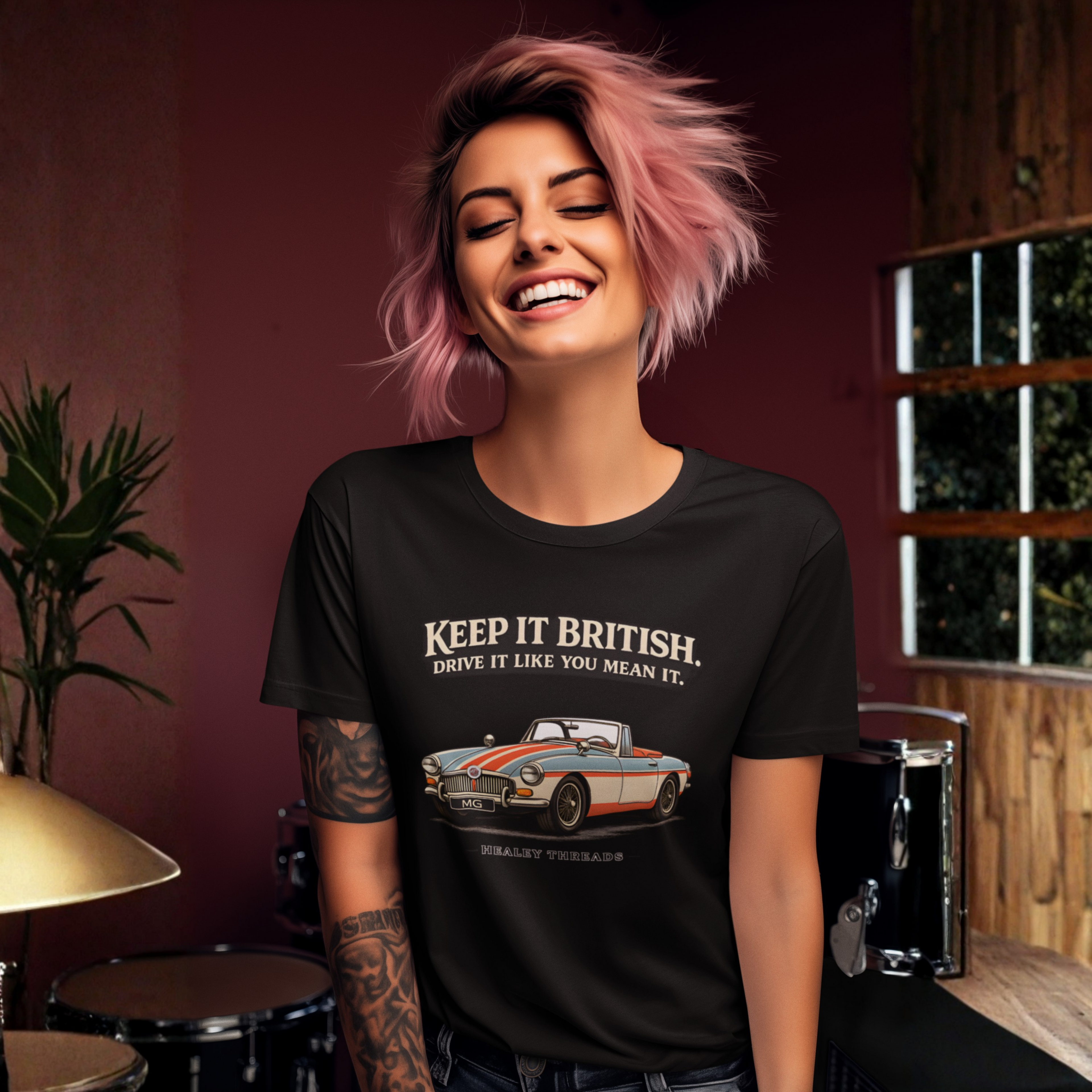 Woman wearing a black t-shirt with a MGB car graphic and text, standing in a room with musical instruments.