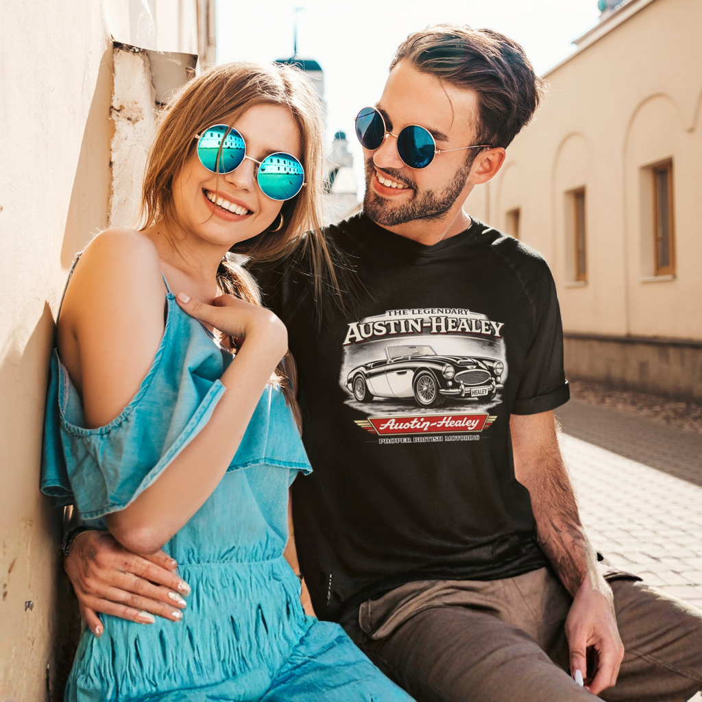 Man and woman sitting together wearing sunglasses, with a focus on the man's Austin-Healey t-shirt.