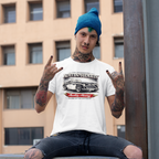Man wearing a white t-shirt with a Healey car graphic and text, sitting outdoors.