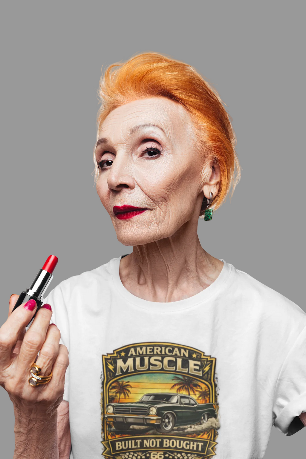 Woman with red hair holding a lipstick, wearing a white t-shirt with 'American Muscle' car graphic.