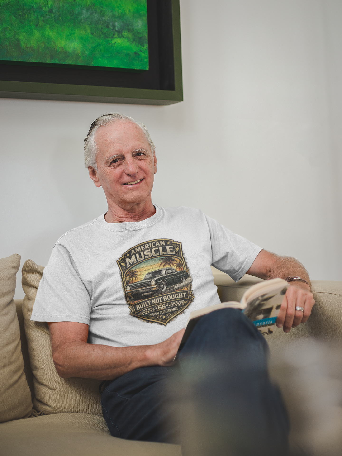 Man sitting on a couch wearing a 'American Muscle' car t-shirt, with a green screen in the background.