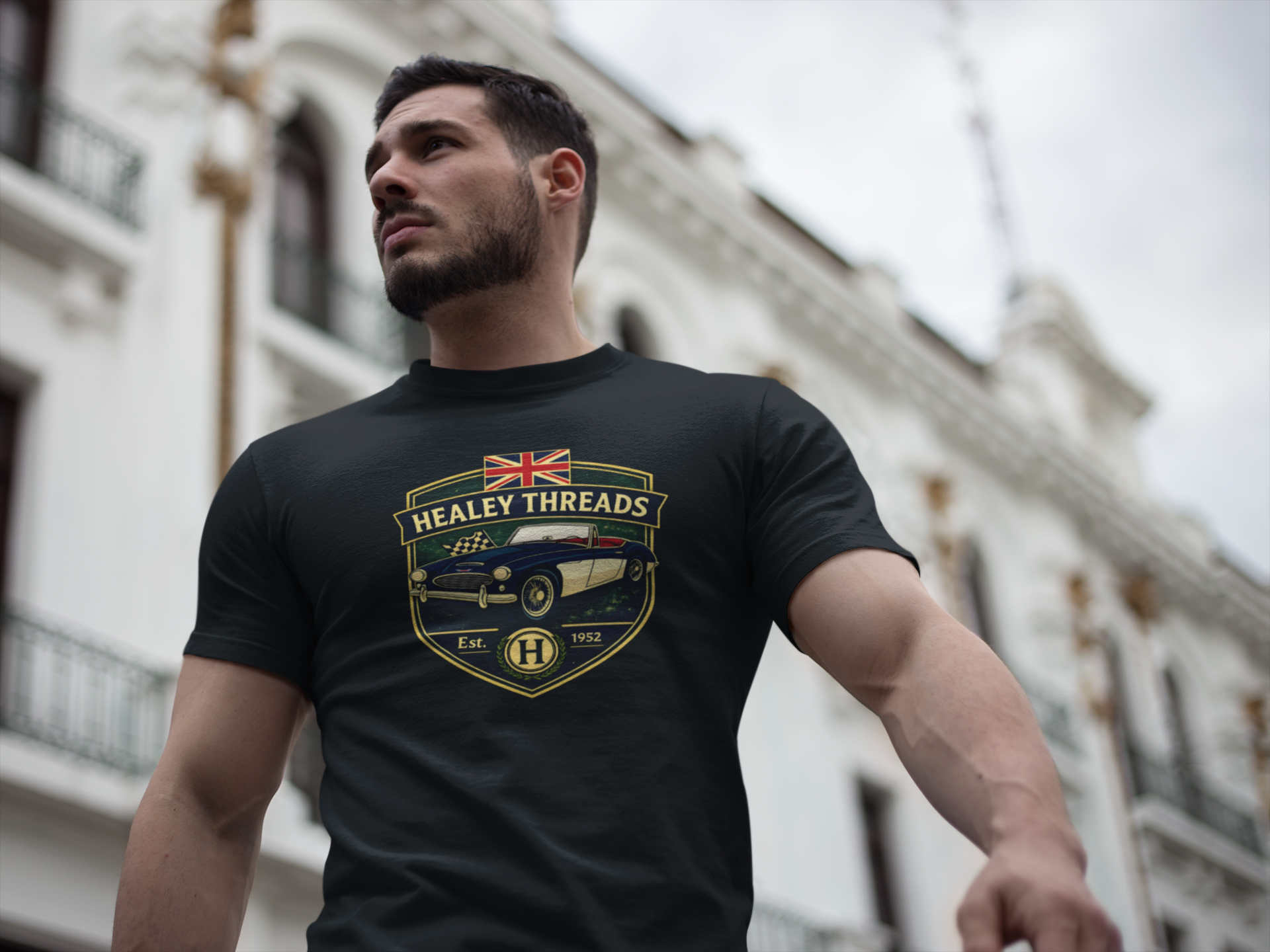 Man wearing a black t-shirt with 'Healey Threads' logo in an urban setting