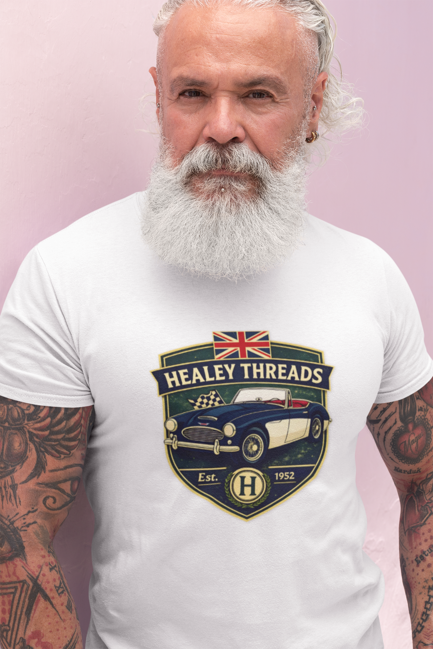 Man wearing a white t-shirt with Healey Threads logo on a pink background