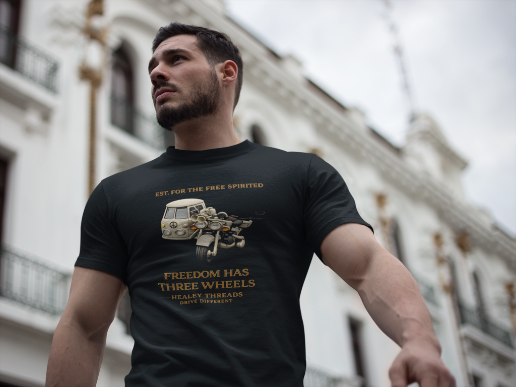 Man wearing a black t-shirt with a tri bike motorcycle and a sidecar graphic design and text, standing in front of a building.