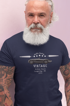 Man wearing a navy blue t-shirt with a vintage car design and text on a pink background