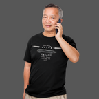 Man wearing a black t-shirt with vintage car design and talking on a phone, on a gray background
