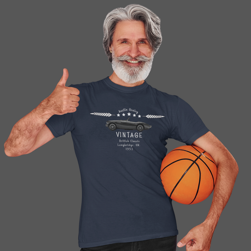 Man wearing a navy blue t-shirt with a vintage car design, holding a basketball on a gray background