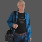Man wearing a black t-shirt with vintage design and a blue jacket, holding a black bag on a gray background