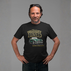 Man wearing a black t-shirt with a classic car graphic design and text, standing against a gray background