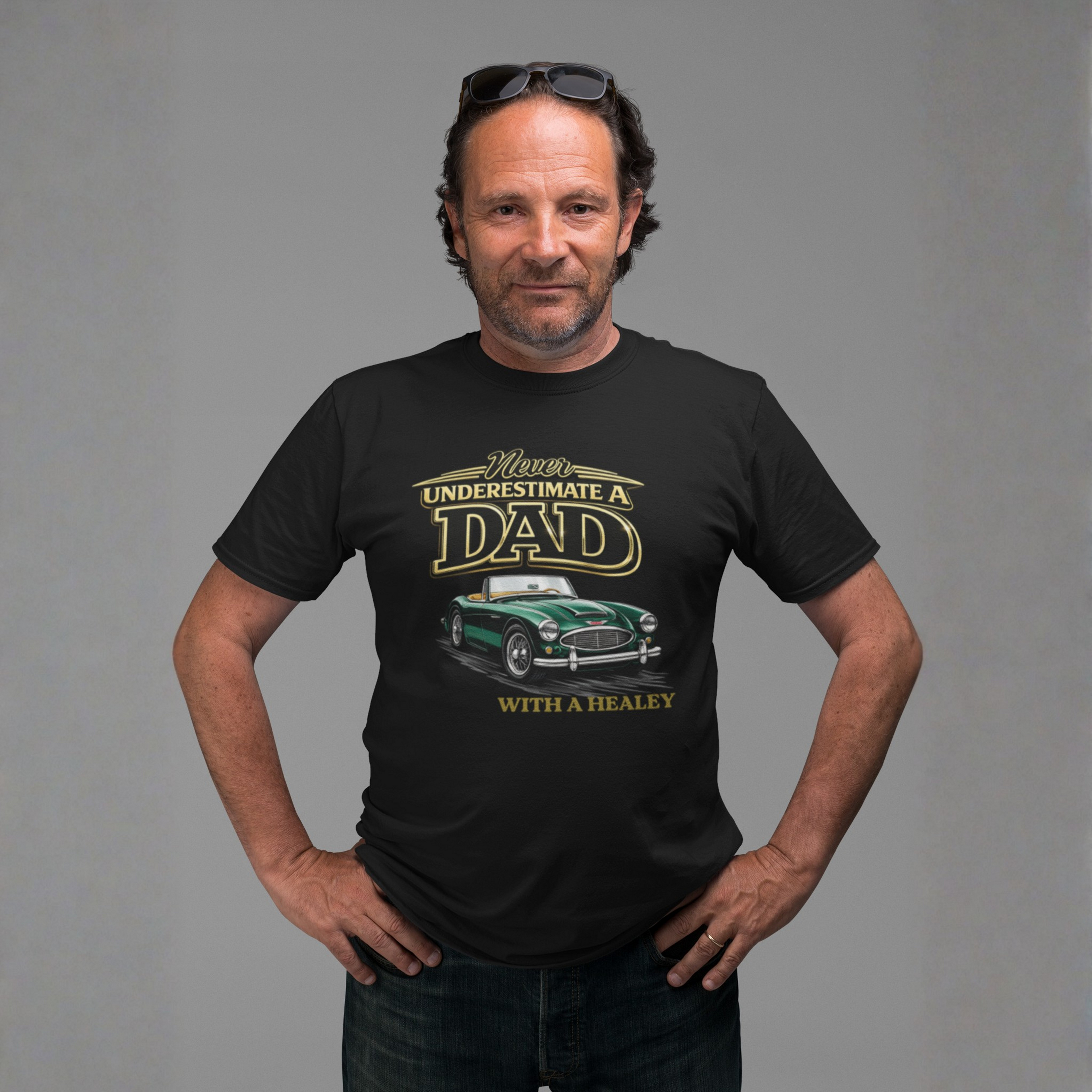 Man wearing a black t-shirt with a classic car graphic design and text, standing against a gray background