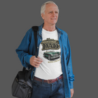 Man wearing a white t-shirt with a classic car graphic design and text, holding a black bag on a gray background