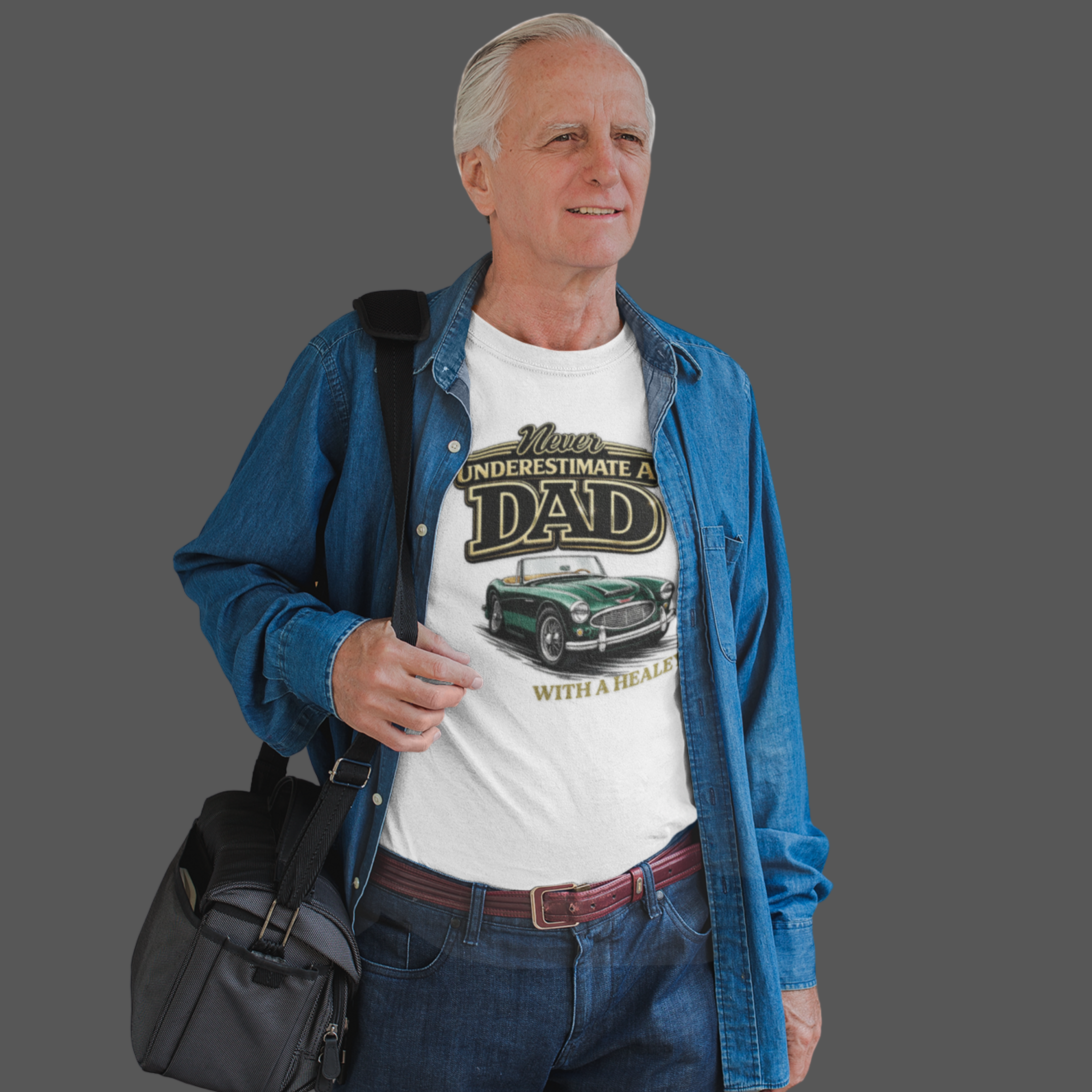 Man wearing a white t-shirt with a classic car graphic design and text, holding a black bag on a gray background