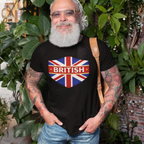 Man wearing a black t-shirt with a British flag design, standing outdoors among greenery.