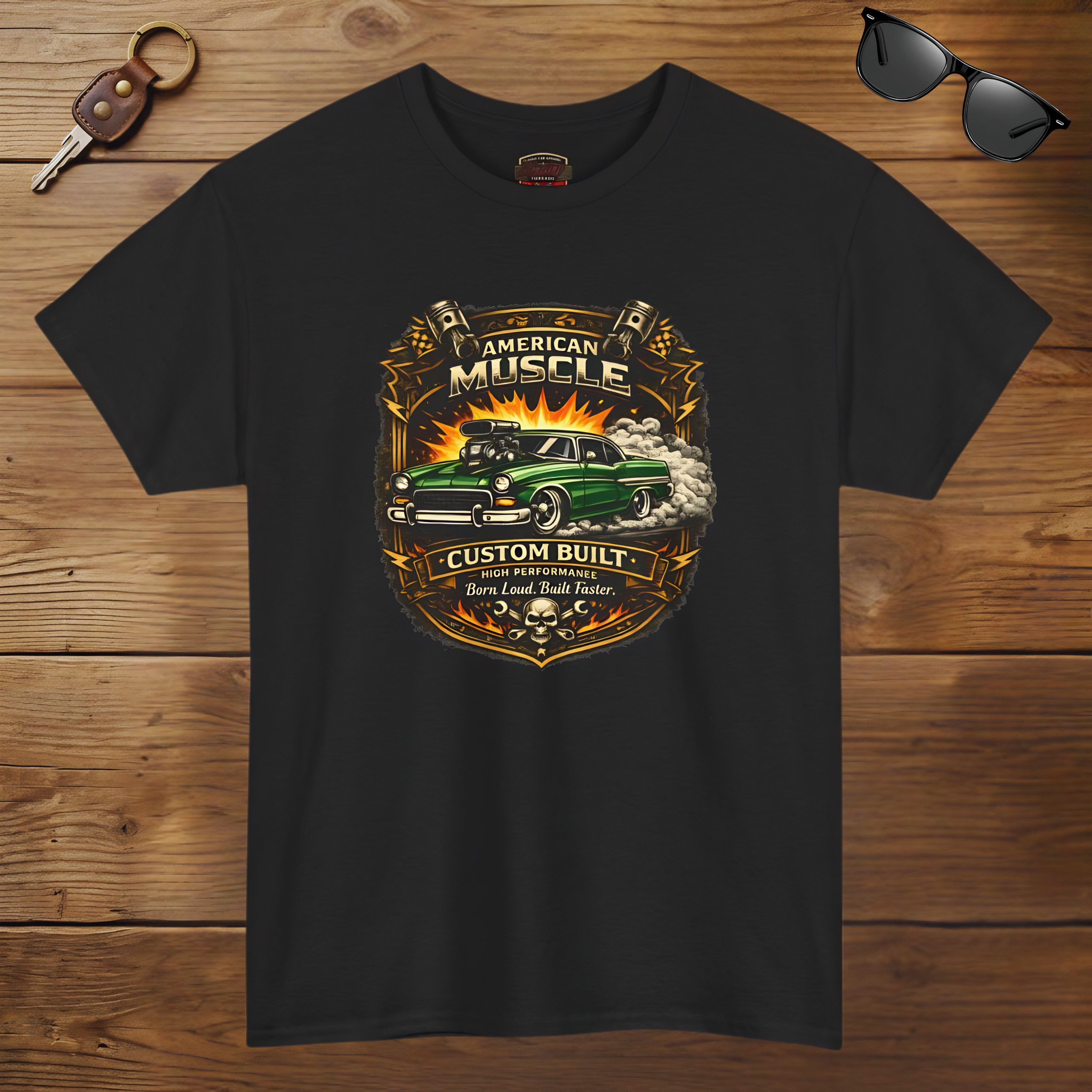 Black t-shirt with 'American Muscle' graphic design on a wooden surface with sunglasses and keychain.