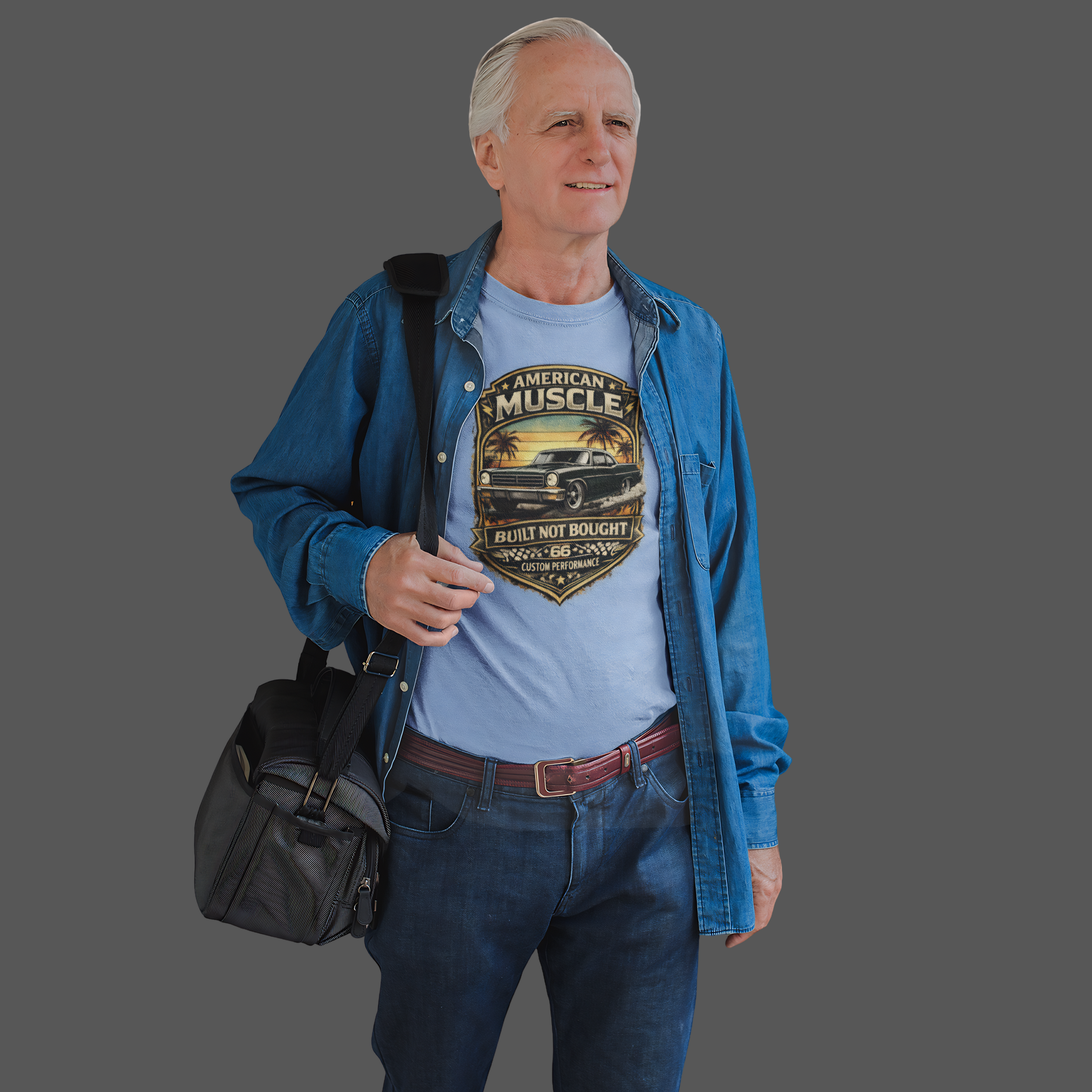 Man wearing a blue jacket and classic car graphic blue t-shirt with a black bag on a gray background