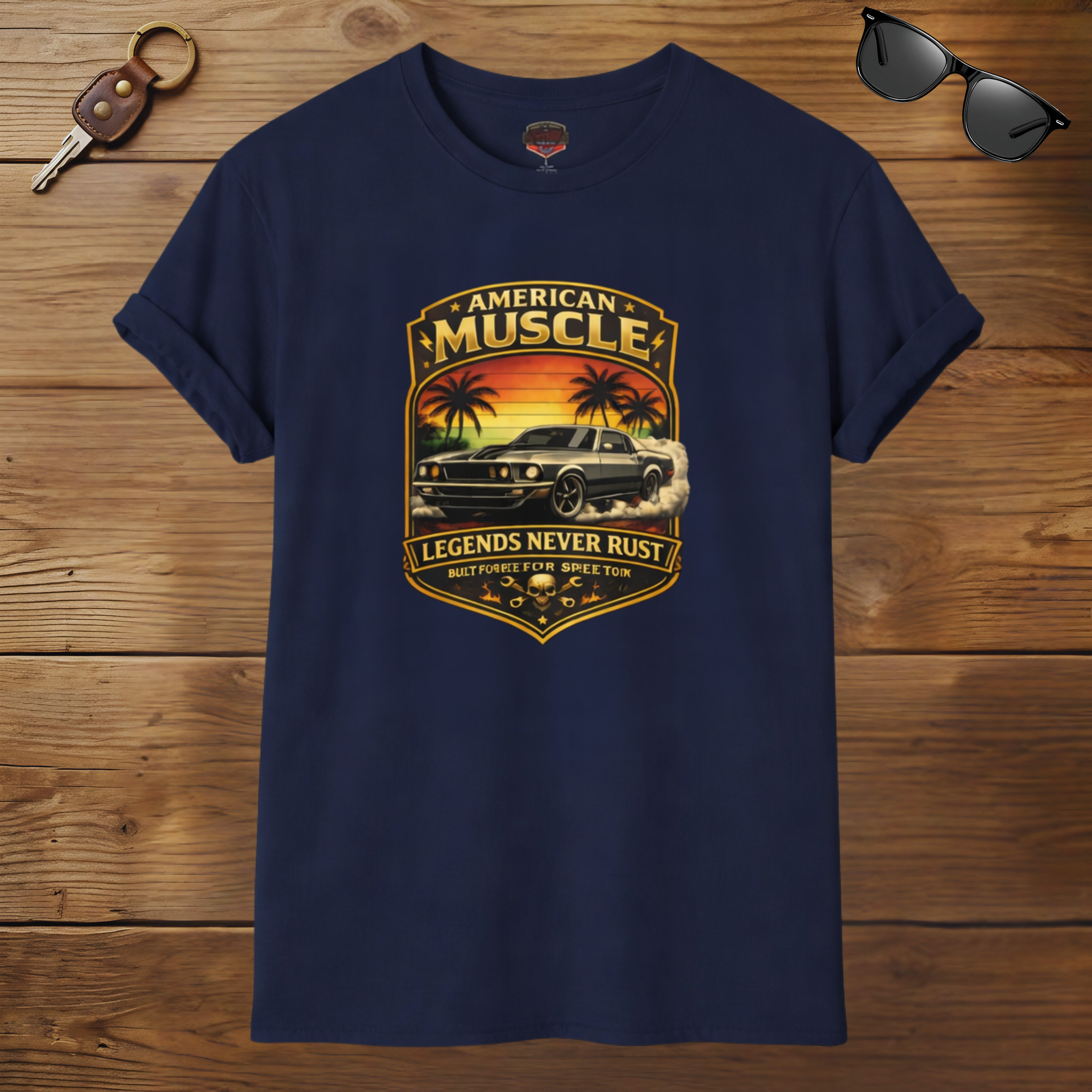 Navy blue t-shirt with 'American Muscle' graphic design on a wooden surface with sunglasses and keychain.