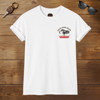 White t-shirt with a graphic Healey design on a wooden surface with sunglasses and keys.