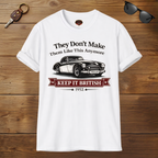 White t-shirt with a graphic of a classic car and text on a wooden surface with sunglasses and keys.