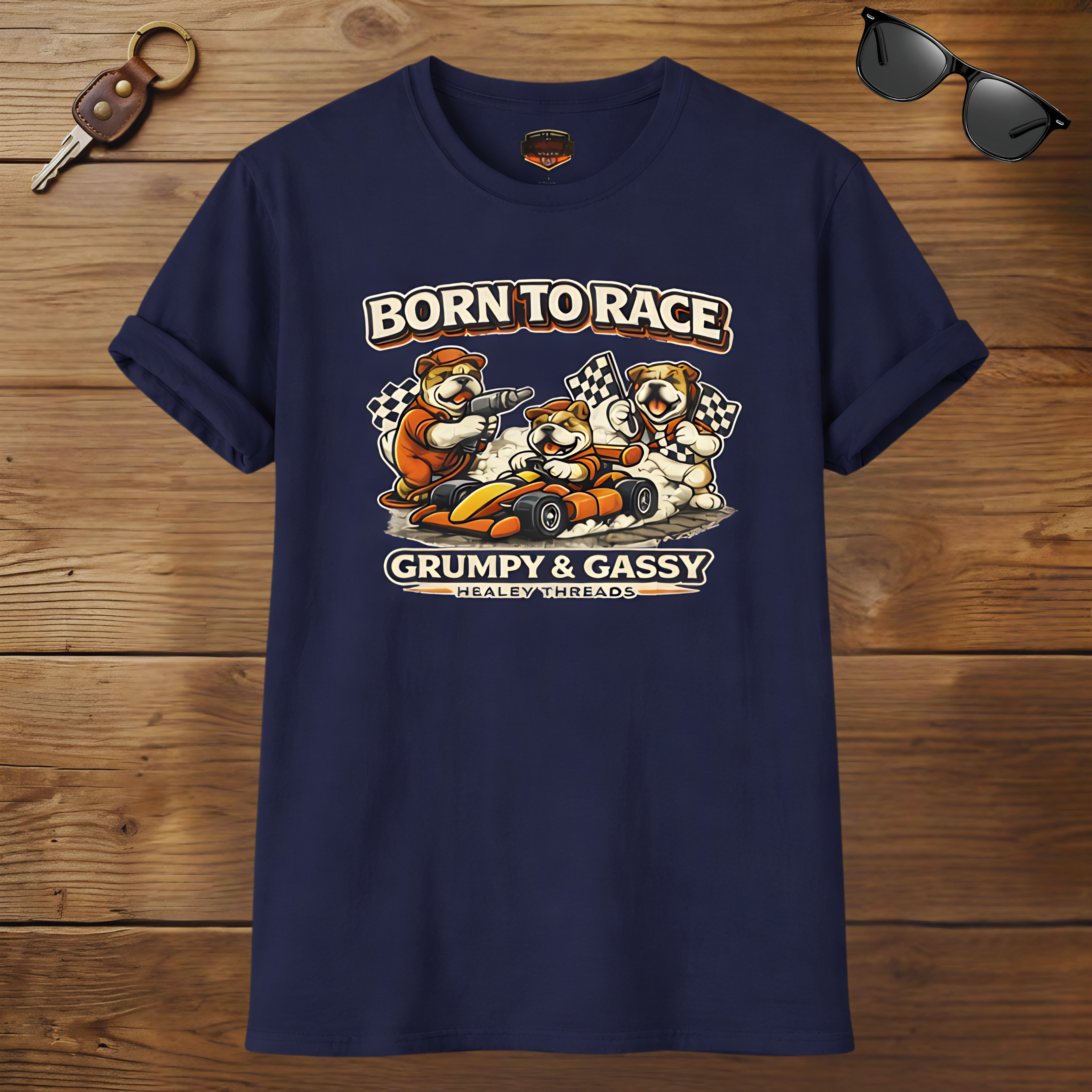 Navy blue t-shirt with 'Born to Race' graphic on a wooden surface with sunglasses and keychain.
