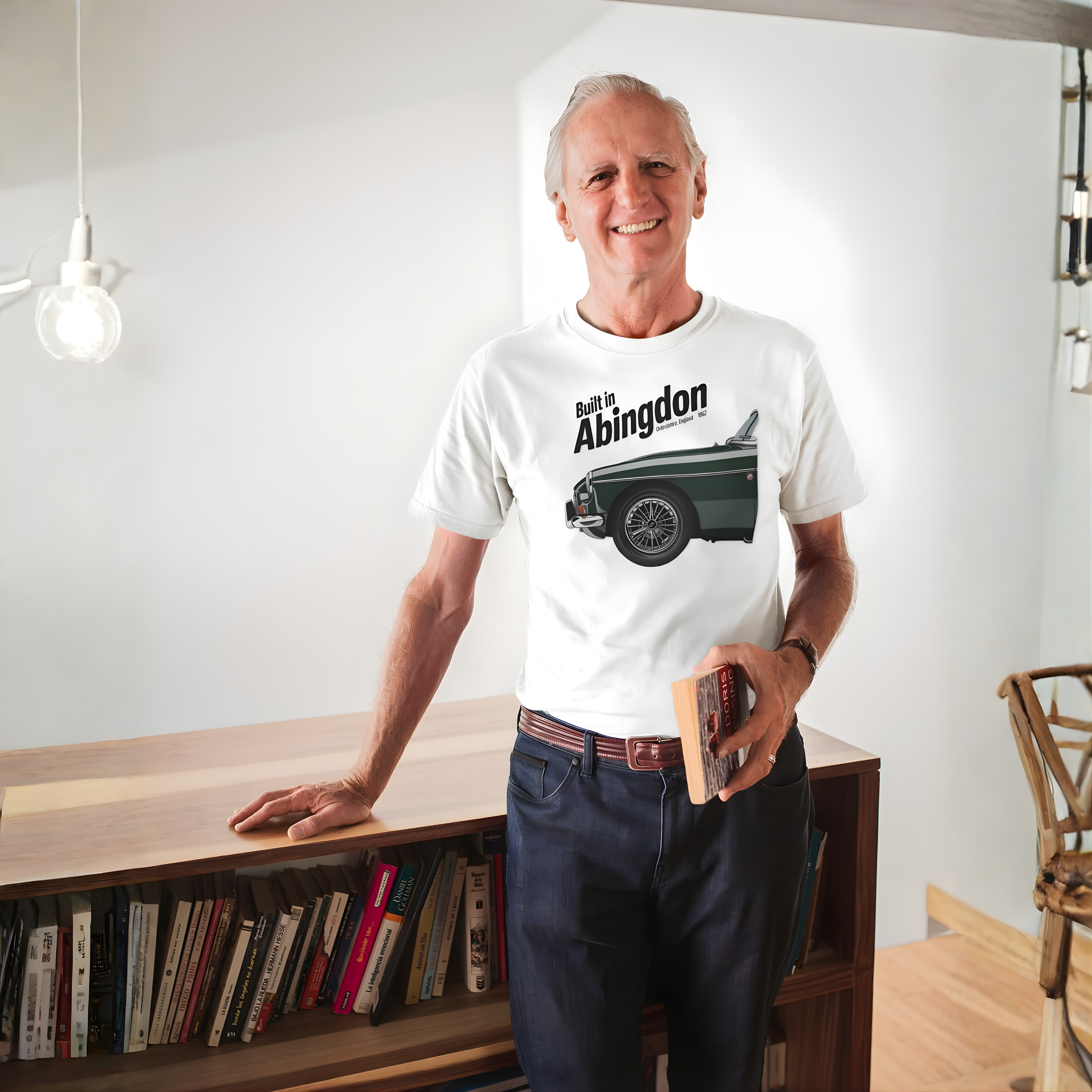 Man wearing a white t-shirt with a classic car graphic design, standing in a room with a bookshelf.