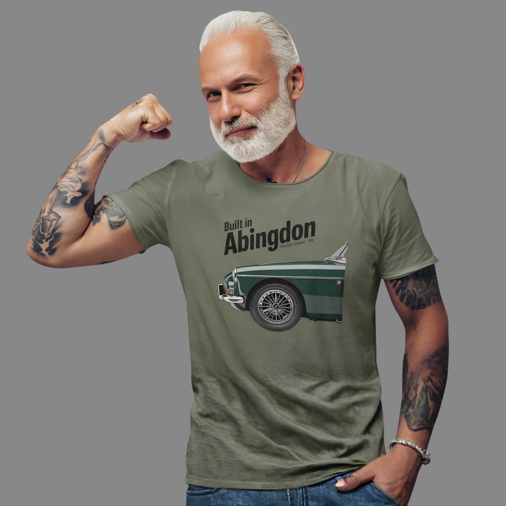 Man wearing a military green t-shirt with a classic car graphic and text, flexing his arm on a gray background