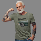Man wearing a military green t-shirt with a classic car graphic and text, flexing his arm on a gray background