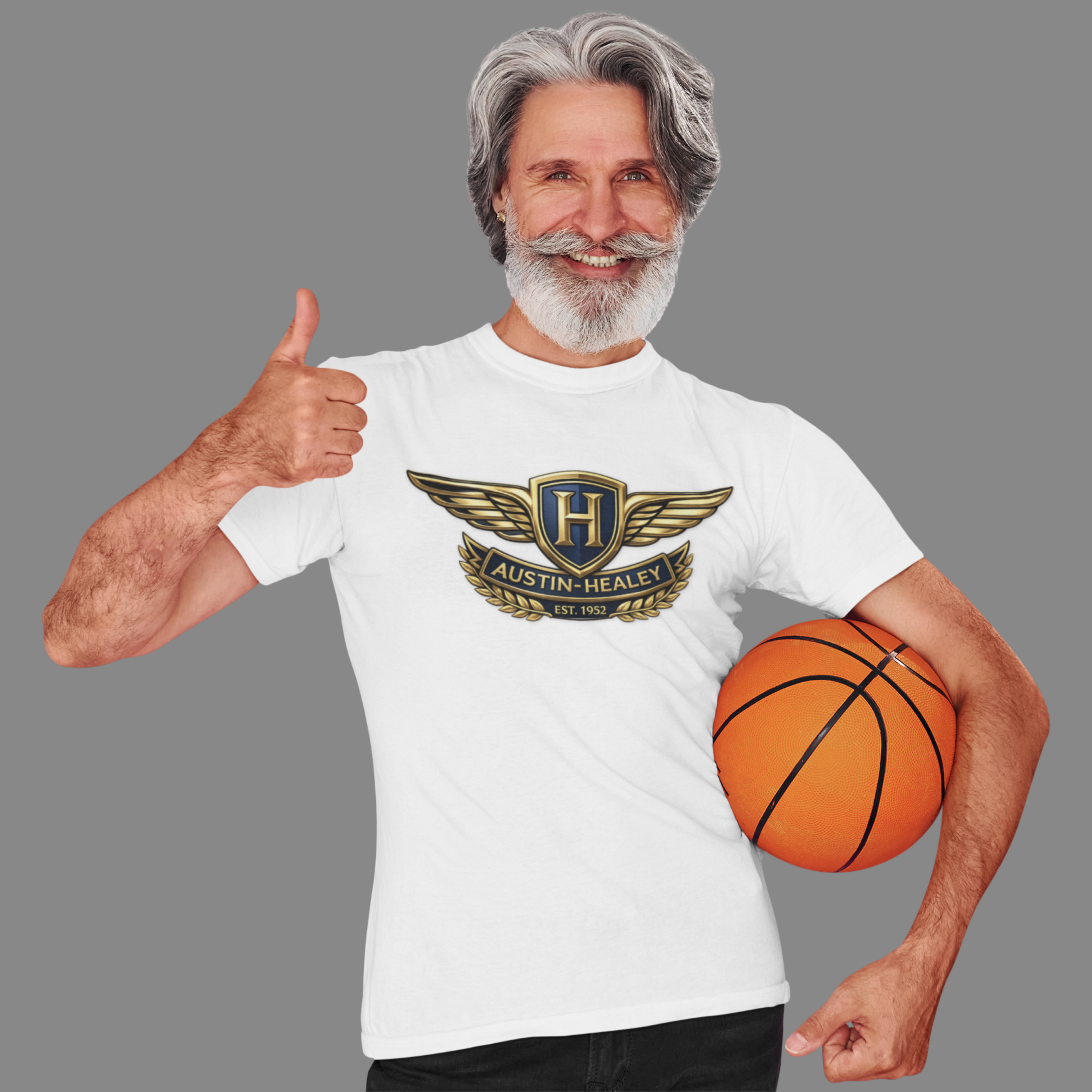Man wearing a white t-shirt with an Austin Healey logo, giving a thumbs up and holding a basketball.