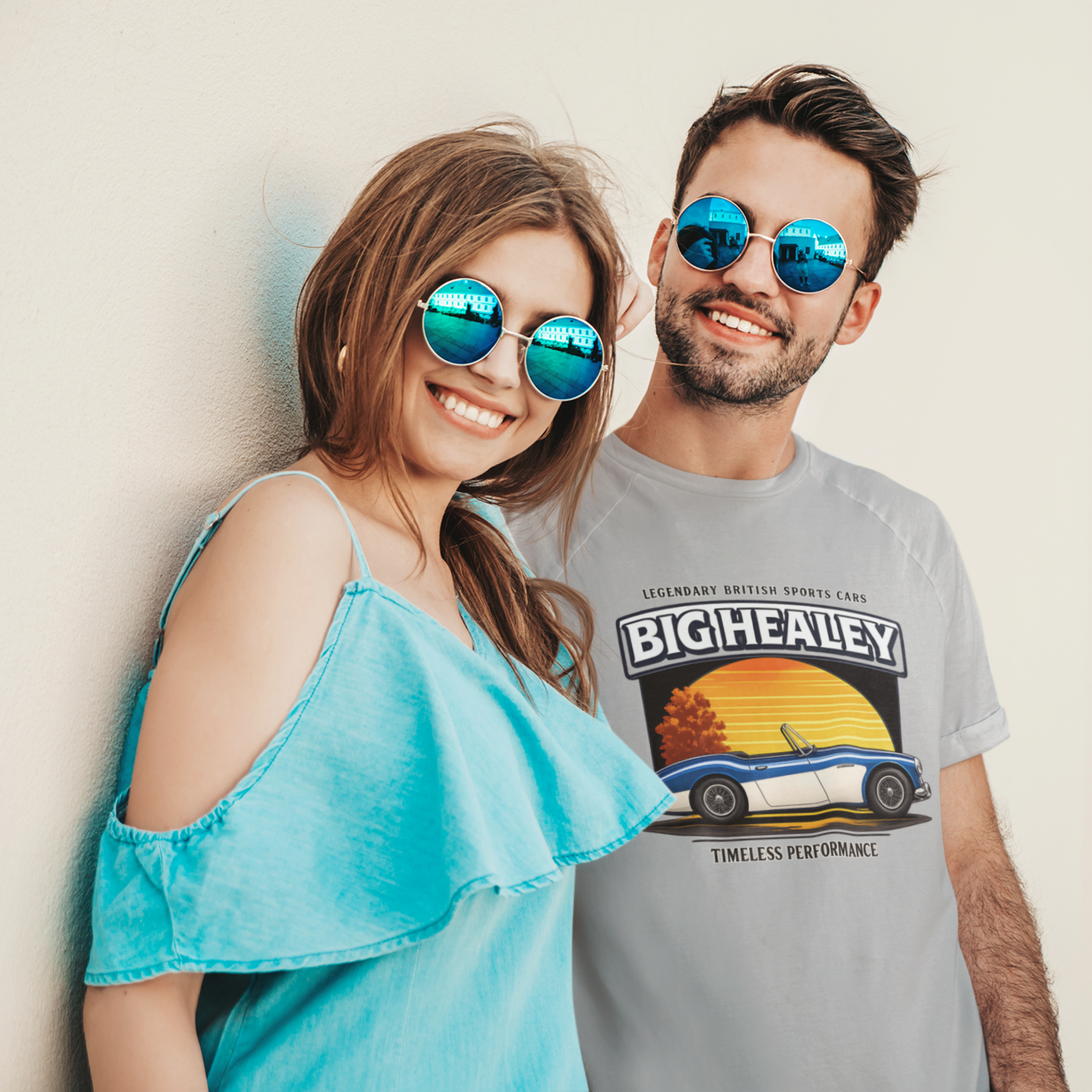 Man wearing a Big Healey graphic gray colored t-shirt featuring a blue and white Austin Healey roadster with retro sunset artwork and vintage British sports car with a woman