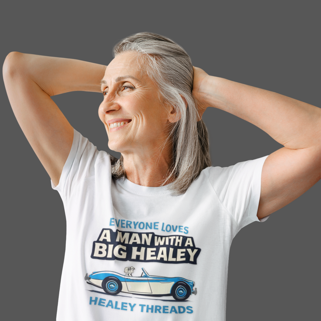 Woman wearing a white t-shirt with a Healey graphic and text, standing against a gray background
