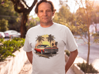 Man wearing a natural t-shirt with a classic car and palm tree design, standing outdoors.