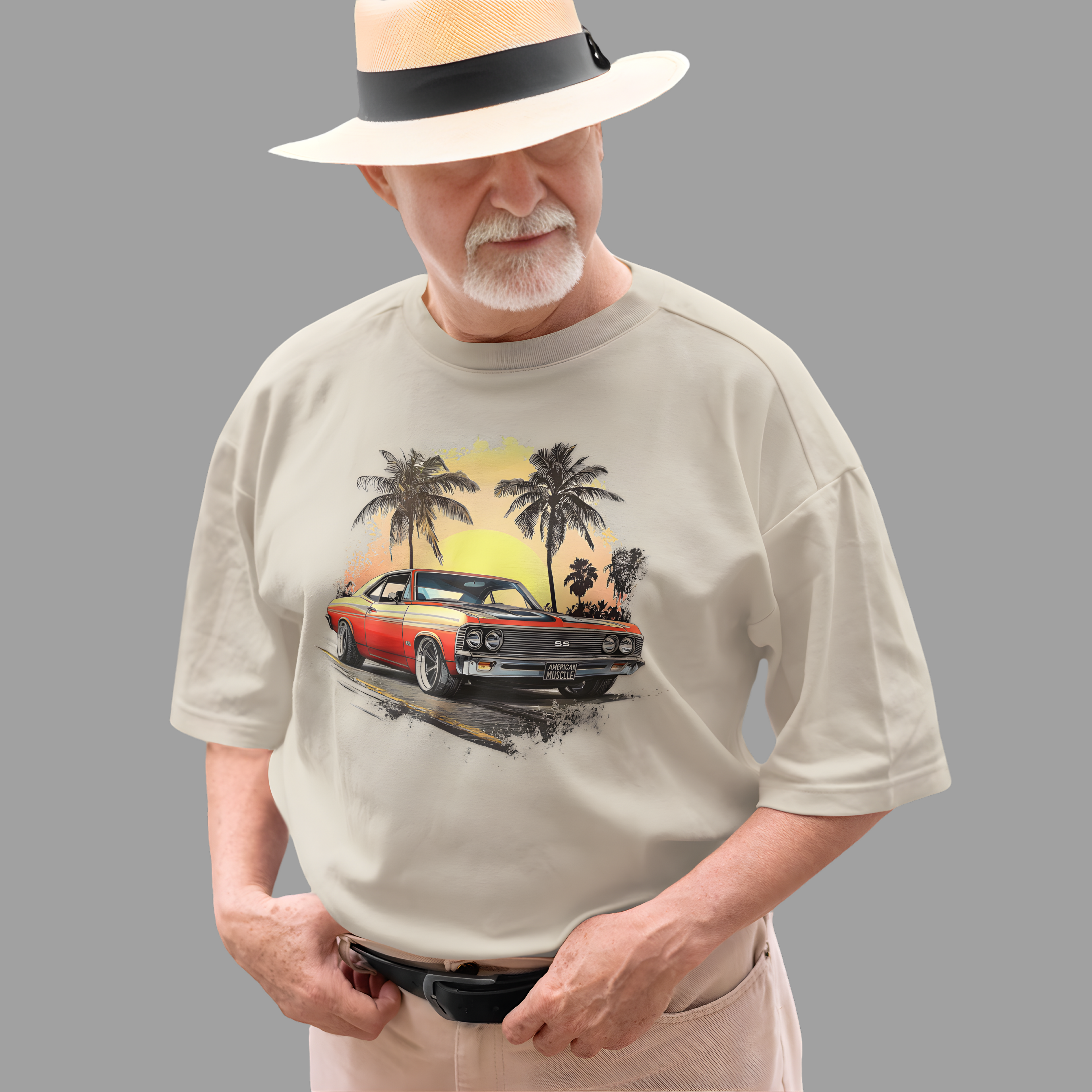 Man wearing a natural t-shirt with a graphic of a classic car and palm trees, standing against a gray background.