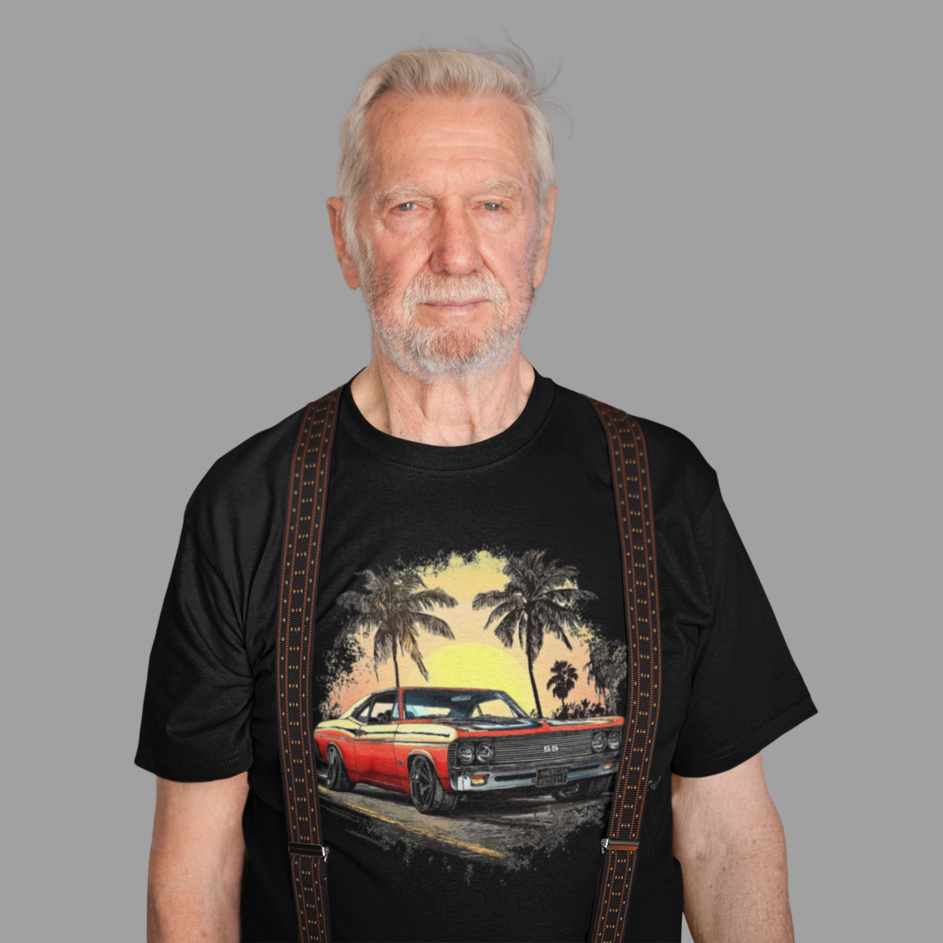 Man wearing a black t-shirt with a graphic of a red classic car and palm trees, standing against a gray background.