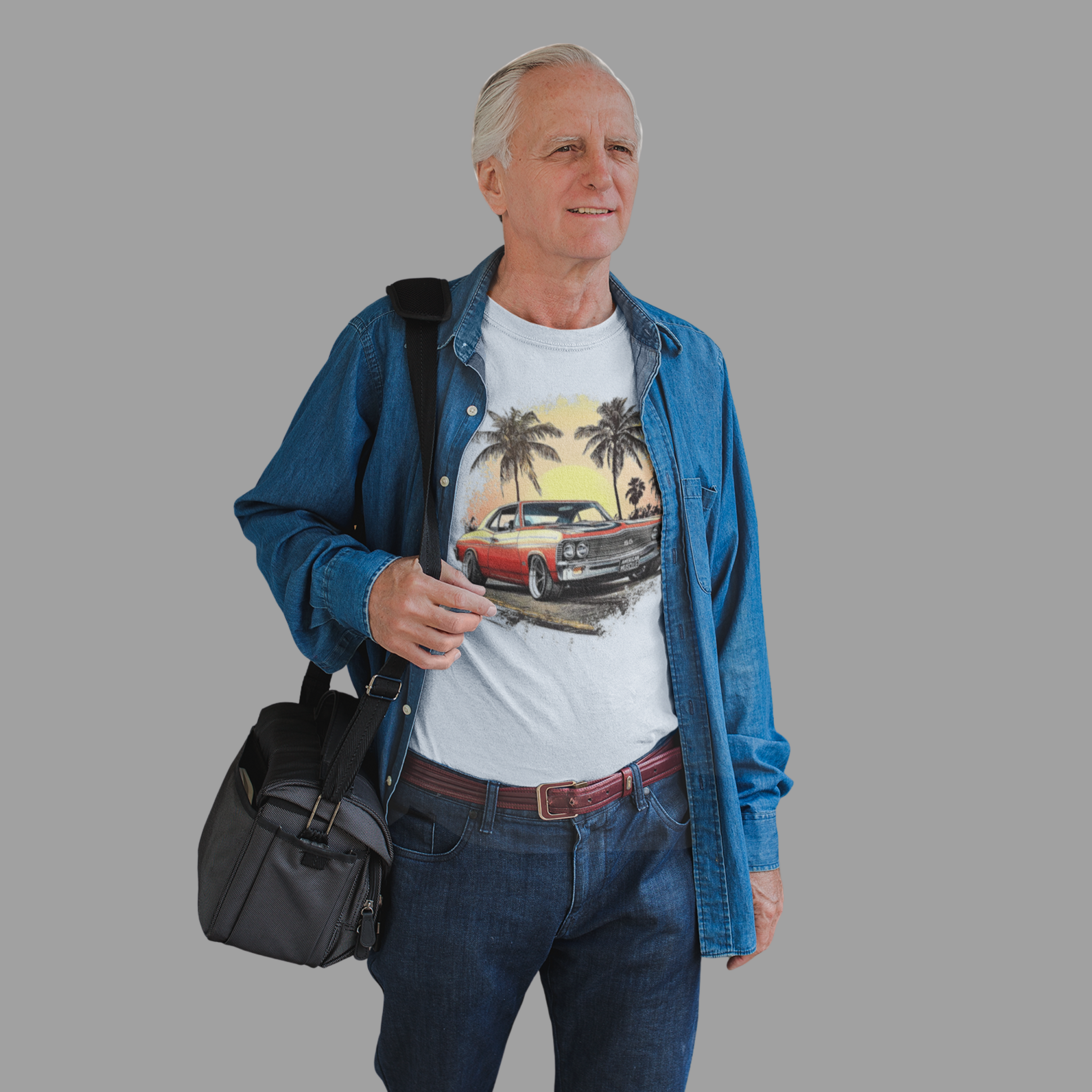 Man wearing a white t-shirt with a graphic classic car design, blue denim jacket, and carrying a black bag on a gray background
