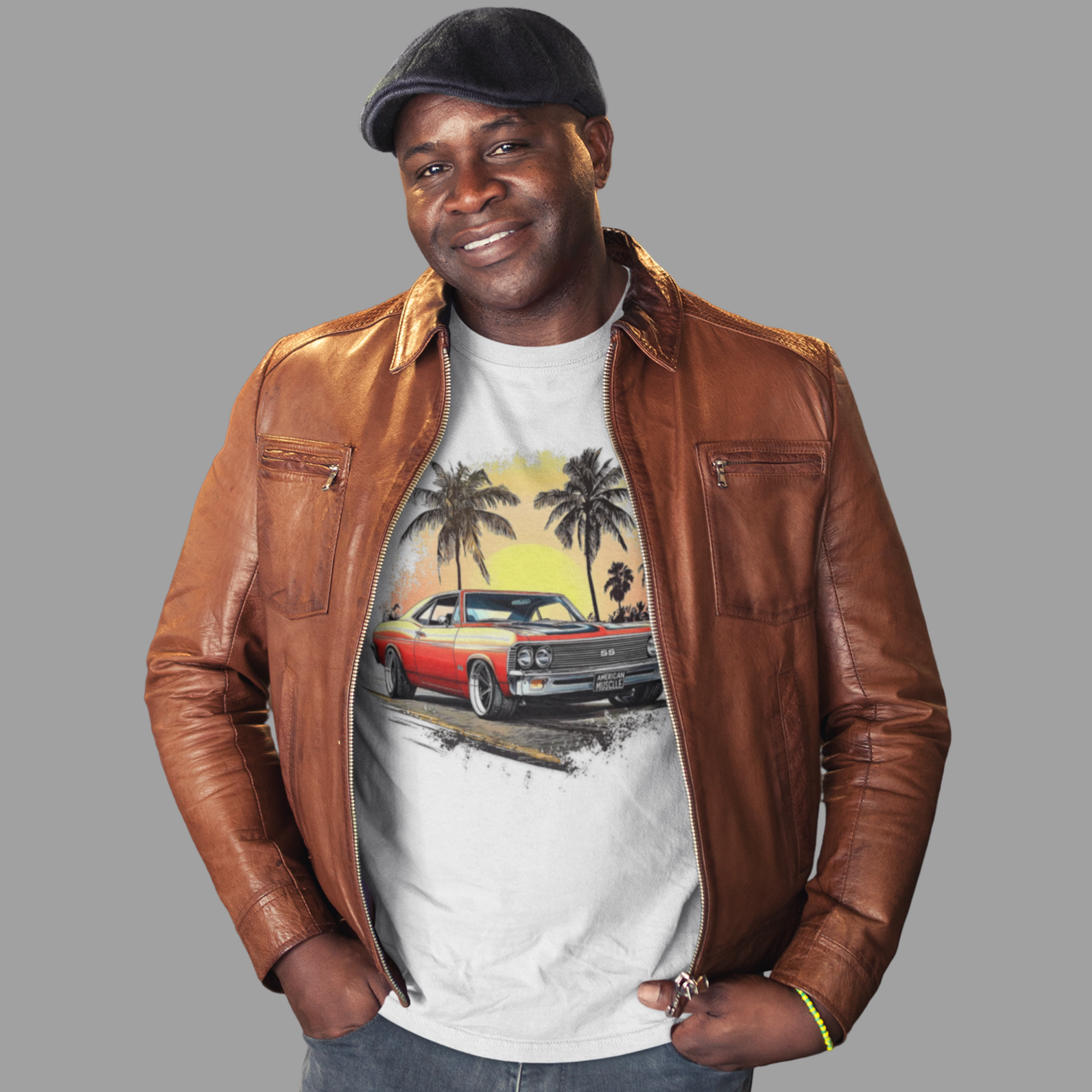 Man wearing a brown leather jacket over a graphic t-shirt with a classic car and palm tree design on a gray background