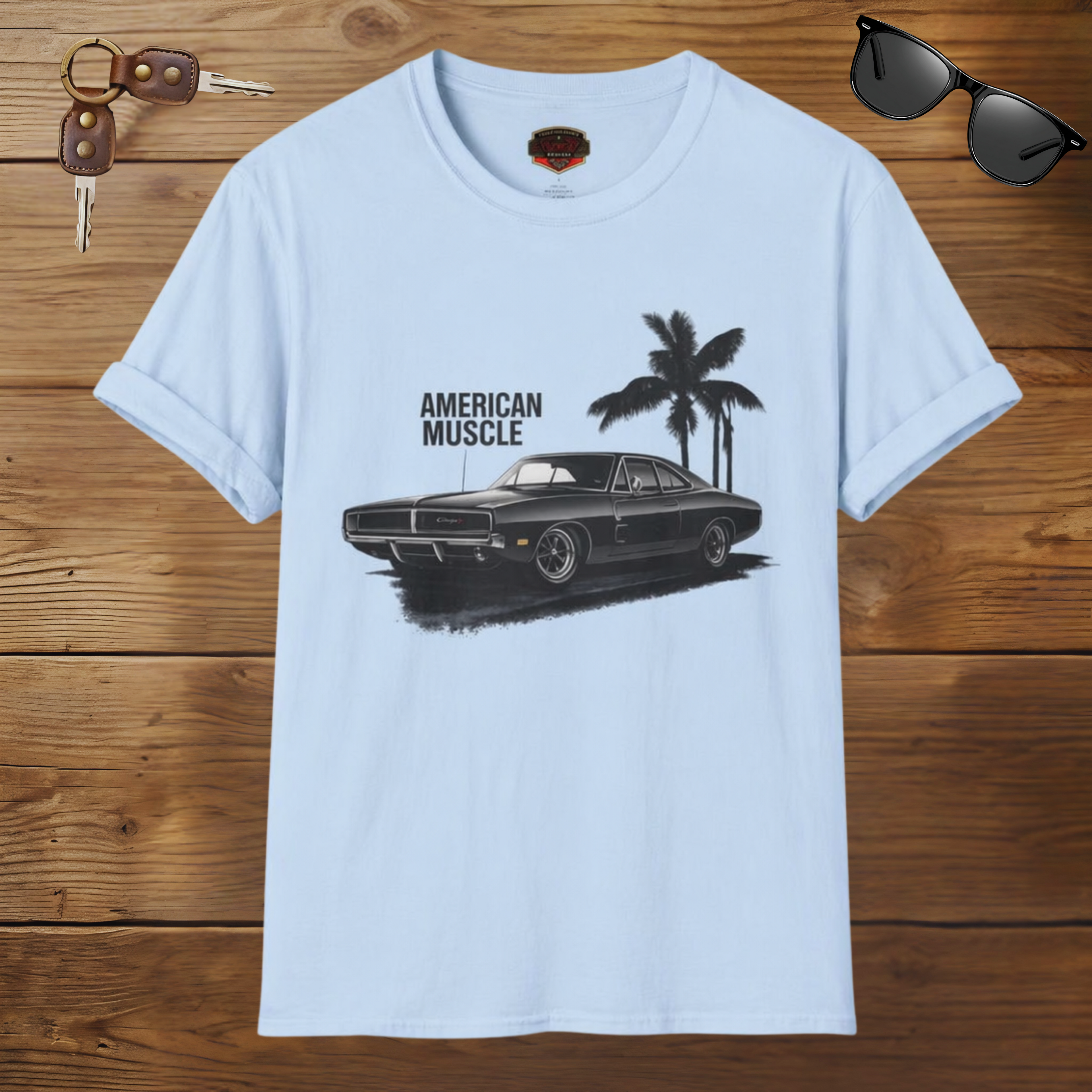 Light blue t-shirt with black muscle car graphic and 'American Muscle' text on a wooden surface.