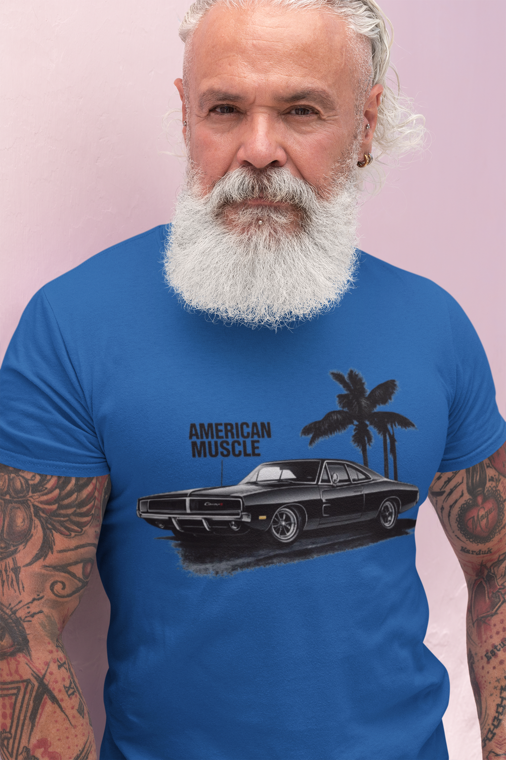 Man wearing a royal blue t-shirt with 'American Muscle' graphic design against a pink background