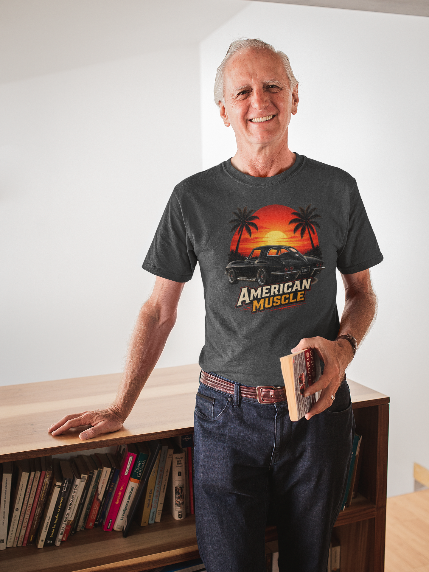 Man wearing a dark heather-shirt with 'American Muscle' graphic design, standing in a room with a bookshelf. 