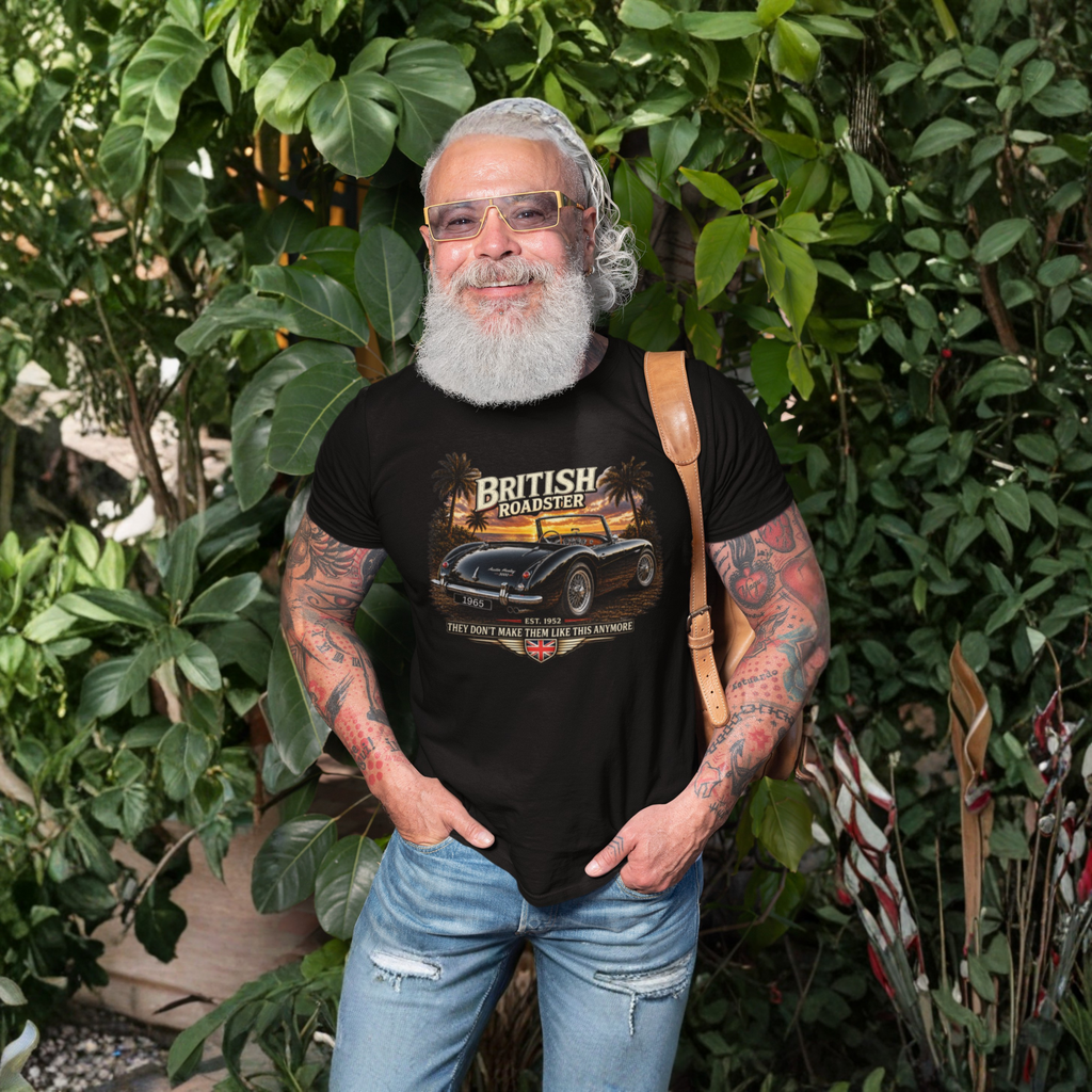 Man wearing a black t-shirt with a car graphic and text, standing outdoors among greenery.