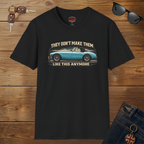 Black t-shirt with a graphic of a classic car and text on a wooden surface with sunglasses and keys.