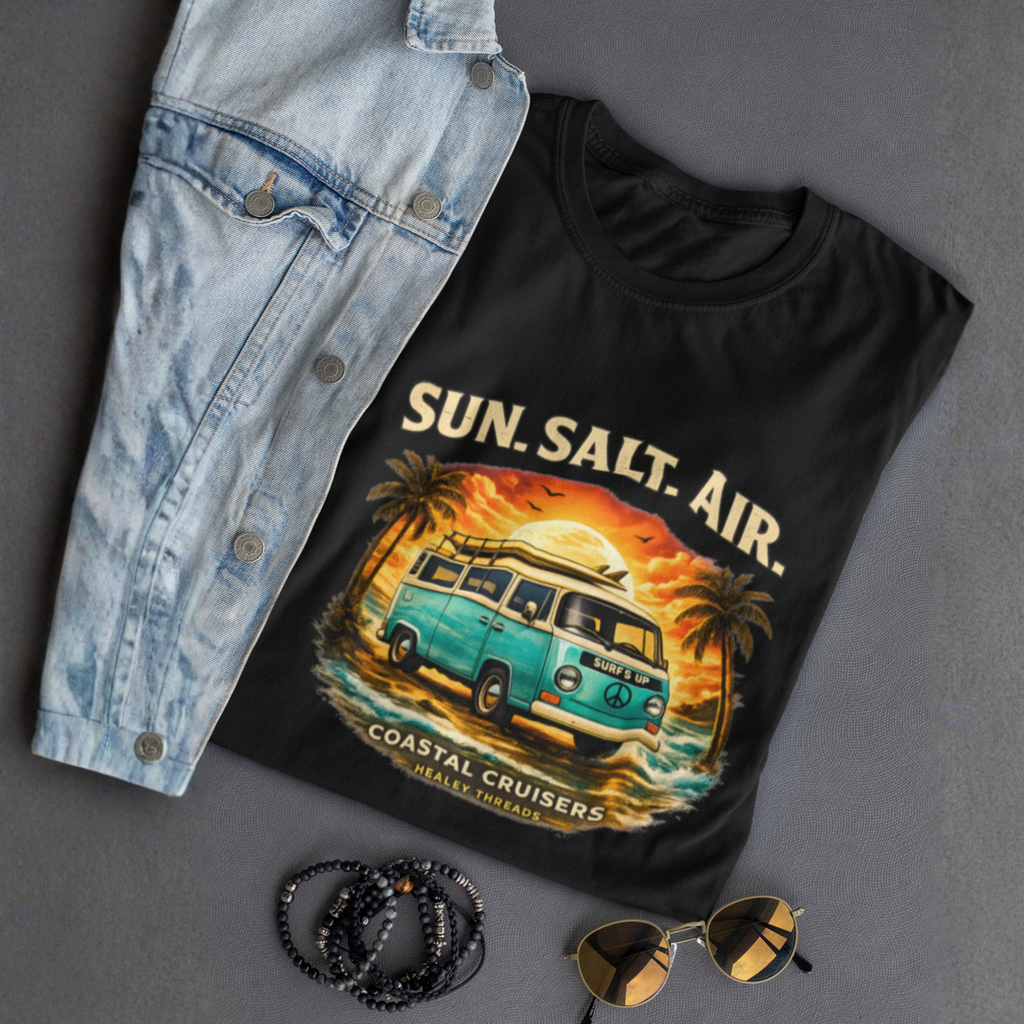 Folded black t-shirt with 'Sun. Salt. Air.' graphic design, denim jacket, sunglasses, and beads on a gray background