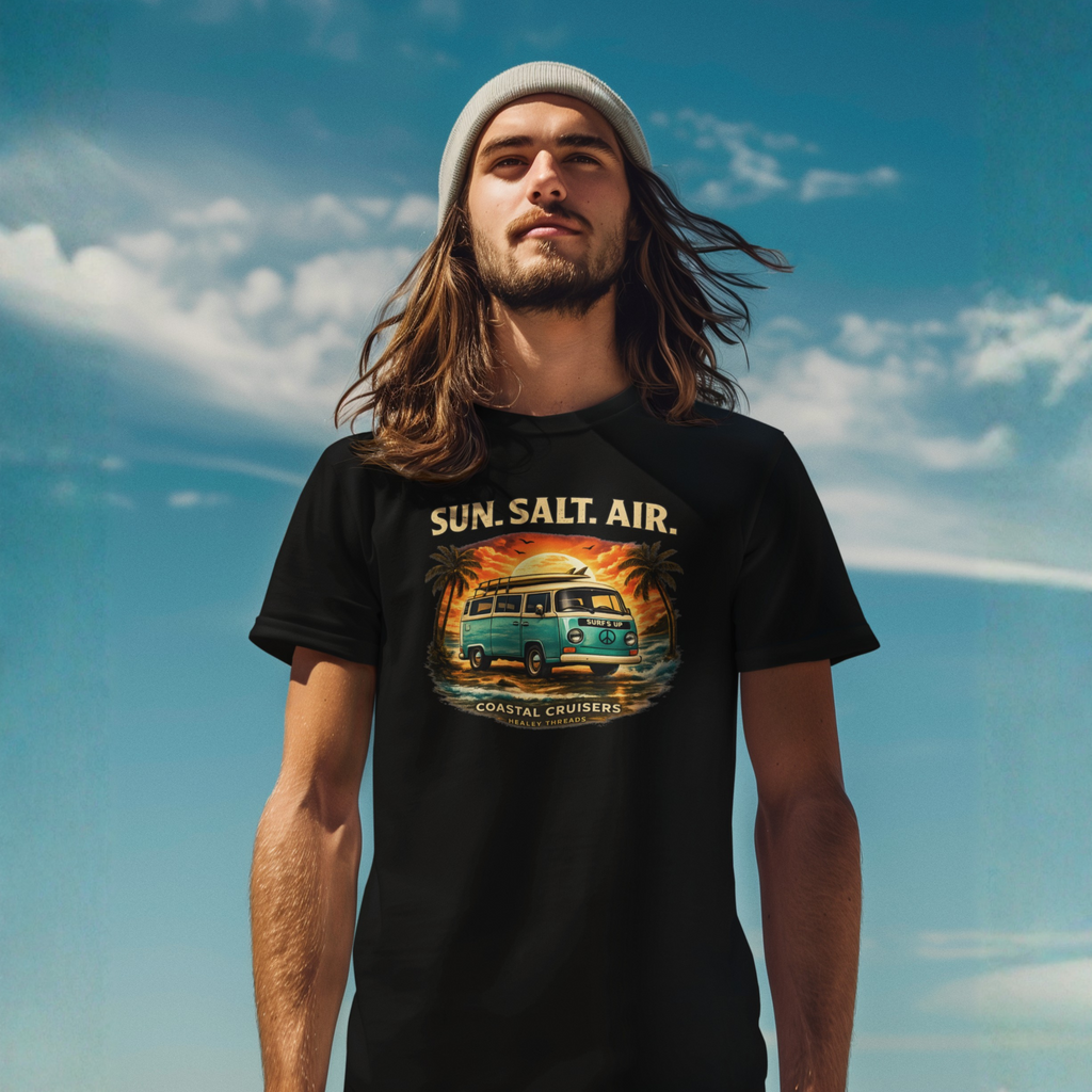 Man with long hair and a beanie wearing a black t-shirt against a blue sky, featuring a retro surf van graphic with "Sun. Salt. Air." and "Coastal Cruisers, Healey Threads" text.