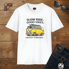 White t-shirt with yellow van graphic and text on a wooden surface with sunglasses and keys.