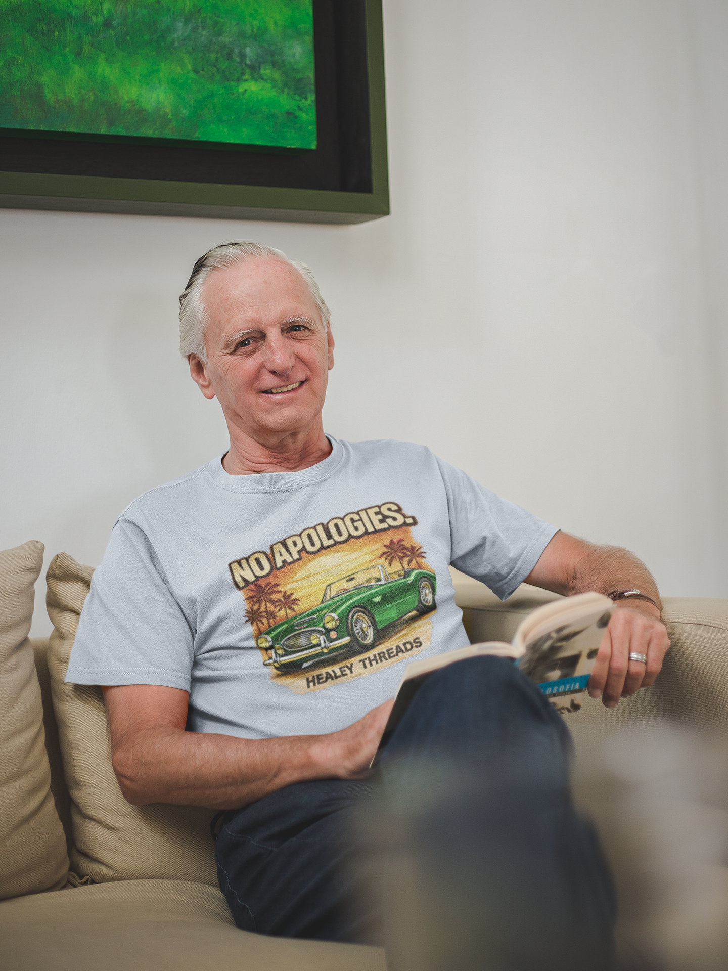 Man sitting on a couch wearing a gray t-shirt with a classic car graphic design.